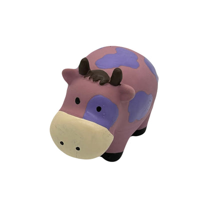 Latex hondenspeeltje koe met paarse vlekken en zwarte hoefjes, liggend op een witte achtergrond.