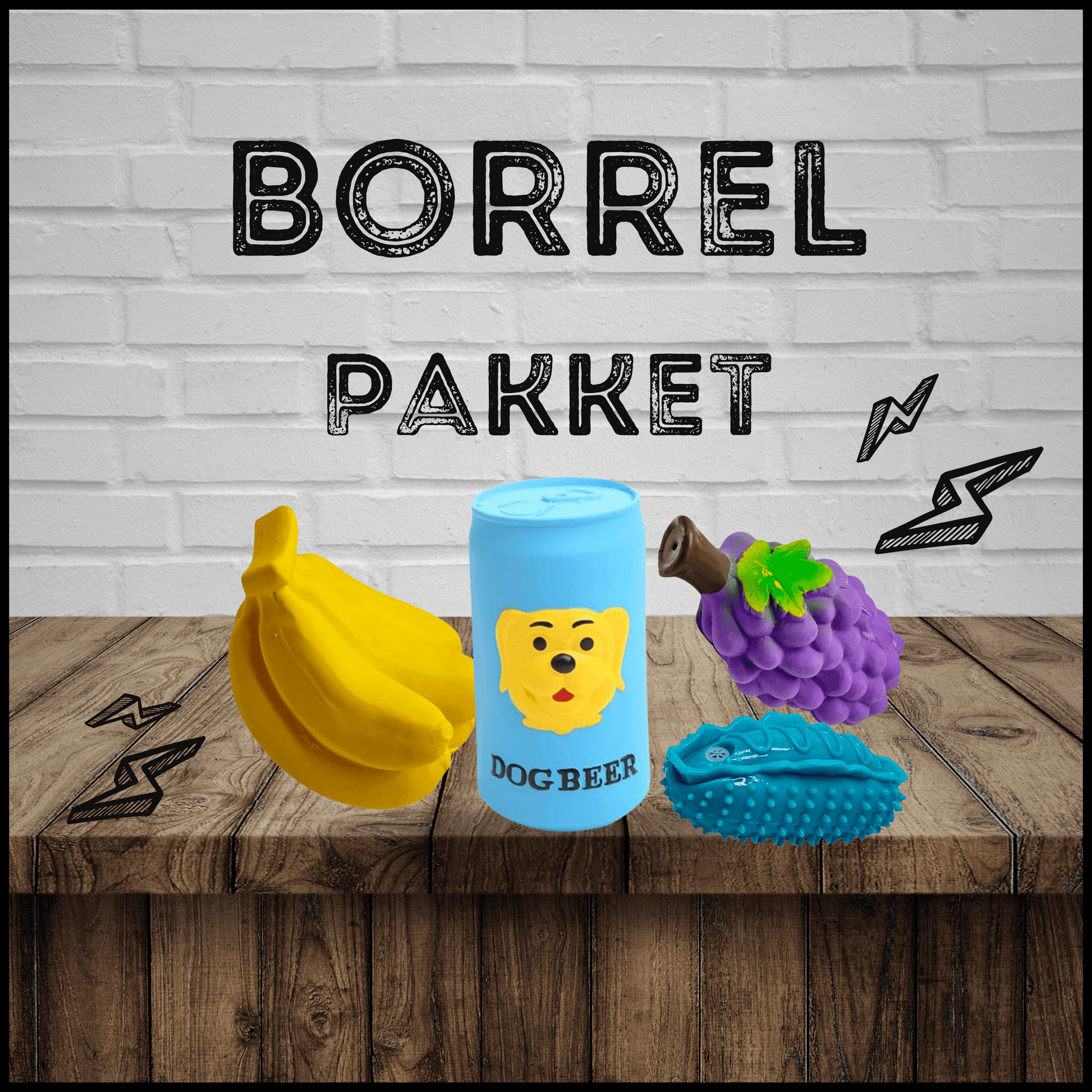 Borrelpakket met hondenspeelgoed: een gele banaan, blauwe dog beer, paarse druif en blauwe auto op een houten tafel.